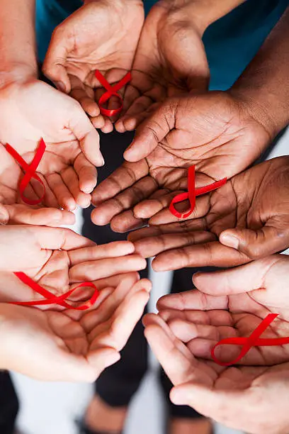 group of multiracial people holding red ribbon for AIDS HIV awareness