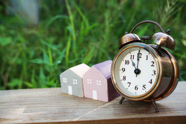 istock Alarm clock and house model on table with natural green background 1538899097