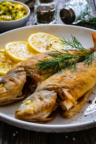 istock Fish dish - fried perch with lemon on wooden table 1538912190
