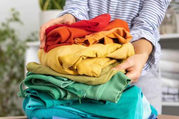 istock A woman holds a stack of brightly colored clothes in her hands. 1538949978
