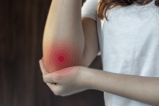 Pain in the elbow joint of Asian young woman. Concept of elbow pain, injury, rheumatism or osteoarthritis.