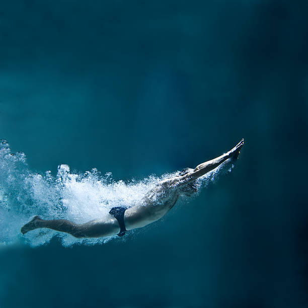 nadador profesional submarinas después del salto - butterfly swimmer fotografías e imágenes de stock