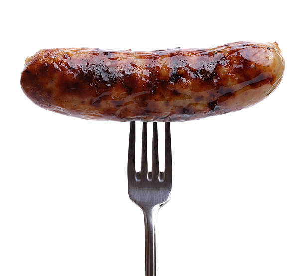 Sausage on a fork Grilled sausage on a fork against white background sausage stock pictures, royalty-free photos & images