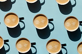 Pattern made of cup of cappuccino on blue background