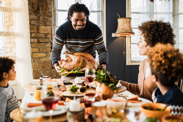 istock Happy black father bringing Thanksgiving turkey to the table. 1539052761