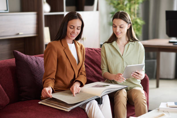 istock Two young smiling female designers discussing textile samples in catalogue 1539085981