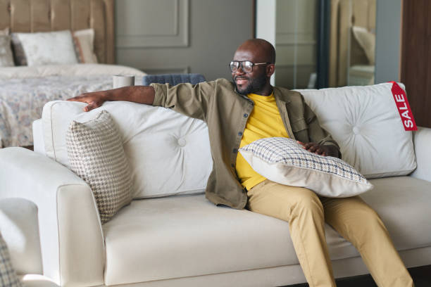 istock Young smiling black man in casualwear sitting on soft comfortable sofa 1539086019