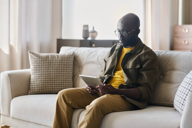 istock Young African American male freelancer with tablet networking on couch 1539086040