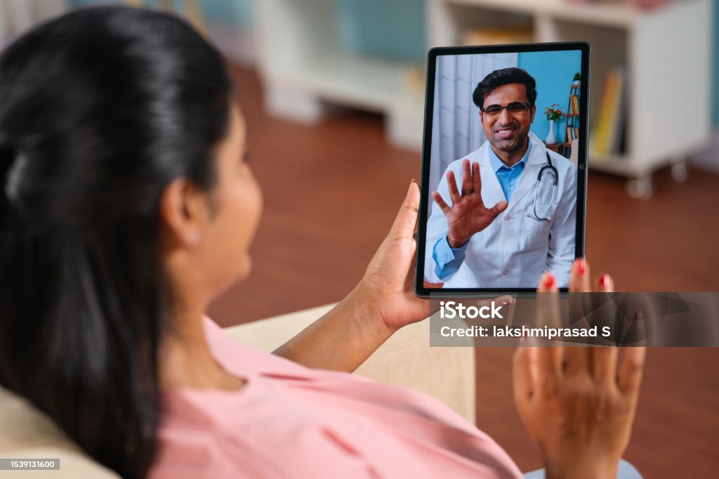 Shoulder shot of indian pregnant woman consulting doctor on video call at home - concept telemedicine, Virtual healthcare and remote consultation. Shoulder shot of indian pregnant woman consulting doctor on video call at home - concept telemedicine, Virtual healthcare and remote consultation Telemedicine Stock Photo