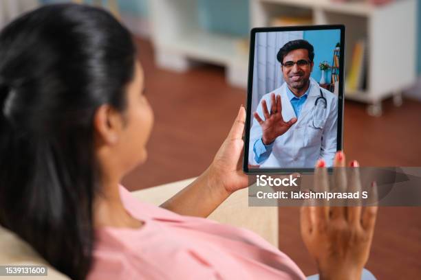 Shoulder Shot Of Indian Pregnant Woman Consulting Doctor On Video Call At Home Concept Telemedicine Virtual Healthcare And Remote Consultation Stock Photo - Download Image Now