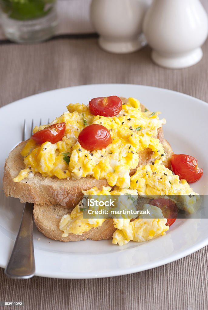 Scrambled egg on toast Toast with scrambled eggs, cherry tomatoes and chives Bread Stock Photo