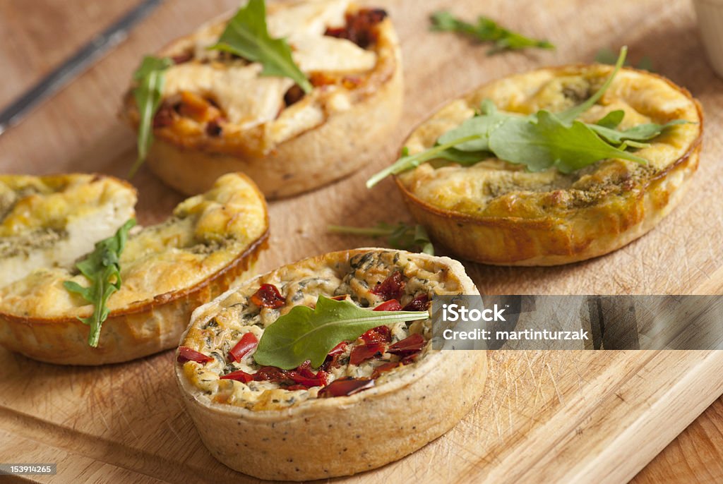 quiche A selection of quiche with rocket and chutney on a wooden board Quiche Stock Photo