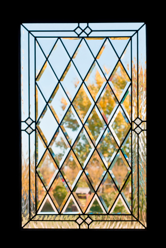 A door window with beveled glass diamond shapes looking outside.