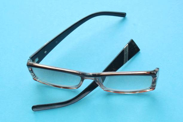 istock Old broken eyeglasses with damaged legs on blue background. Poor eyesight. Reuse and repair concept. Idea of health 1539176841