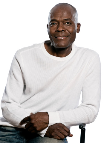 Portrait of a casual handsome afro American man smiling while sitting in studio isolated on white  background