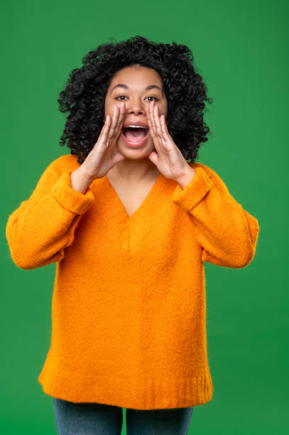 istock Dark-haired woman in orange calling someone 1539182595