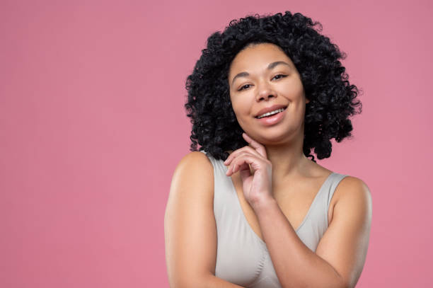 istock Smiling curly-haired brunette woman on pink background 1539183128