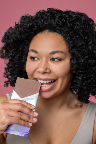istock Dark-skinned woman eating chocolate and looking contented 1539184718