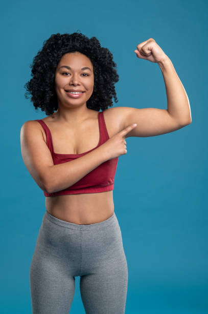 istock Cute smiling woman showing her muscles 1539185262