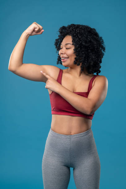 istock Cute smiling woman showing her muscles 1539185778
