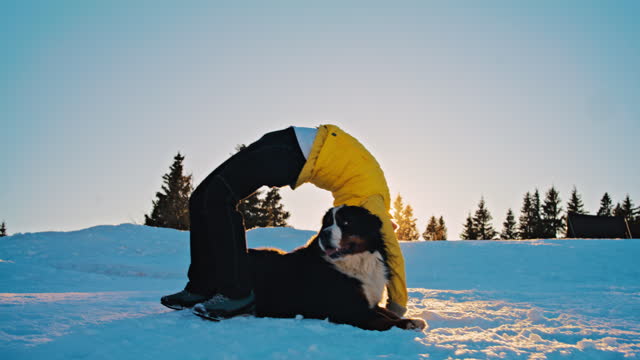 SLO MO Woman doing wheel pose on a snowy slope