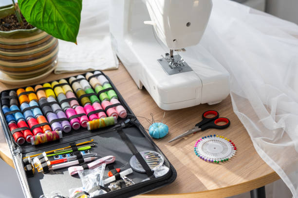 Sewing layout with multicolored spools of thread close-up, needles, electric sewing machine. Filling the thread into the sewing needle, adjusting the tension. hobby, home business