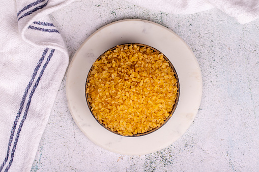 Bulgur on stone background. Bulgur wheat grains in bowl. Top view