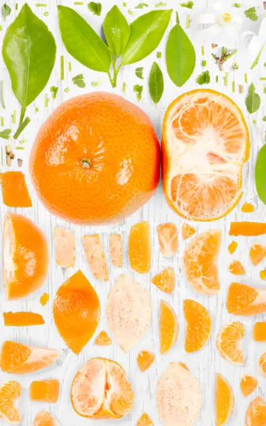 Abstract background made of Tangerine fruit pieces, slices and leaves on wooden background.