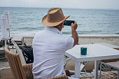 Old tourist using mobile phone on seashore