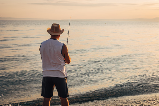 Hobby, a man is fishing with a fishing rod on the seashore