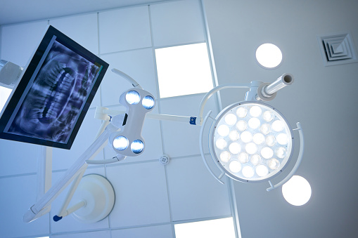 Surgical lamp and monitor with the image of a dental x-ray at the workplace of a dentist in modern clinic