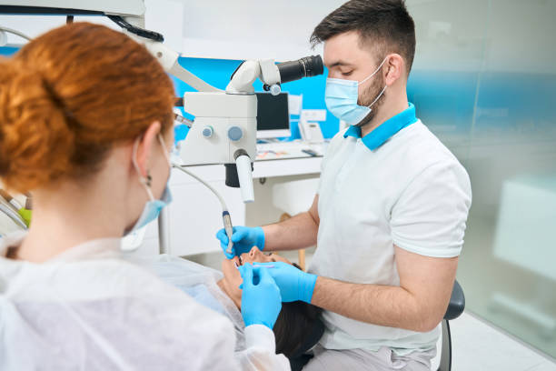 Doctor treats a young female tooth under a microscope stock photo