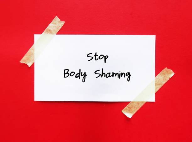 istock Note stick on red background with handwritten text STOP BODY SHAMING , no more humiliation about another body shape , size or criticizing appearance through negative judgment 1539346302