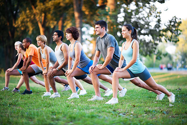 gruppo di persone facendo esercizi di stretching. - yoga exercising outdoors group of people foto e immagini stock