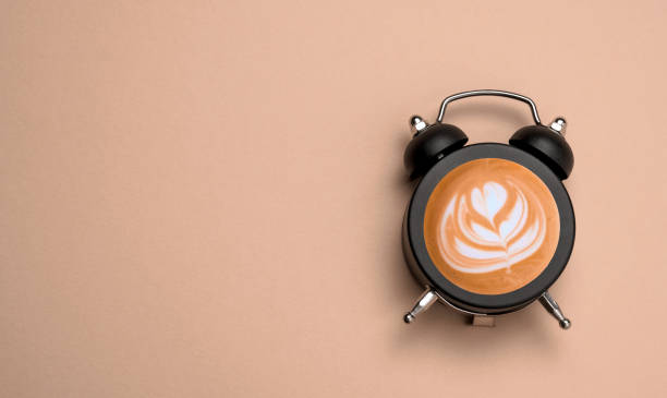 istock Top view flat lay alarm clock with coffee into it. Beige light brown background copy space. Minimal art coffee collage. 1539416734