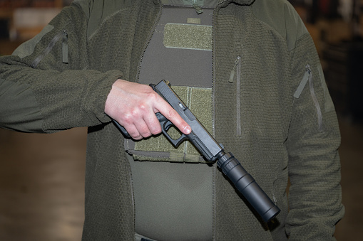Man holding pistol with a silencer in his hand ,high quality photo