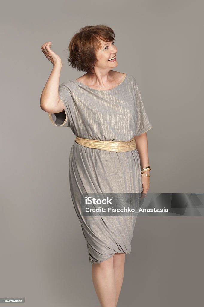 Beautiful fashionable mature woman in grey dress. Studio shot. Dress Stock Photo