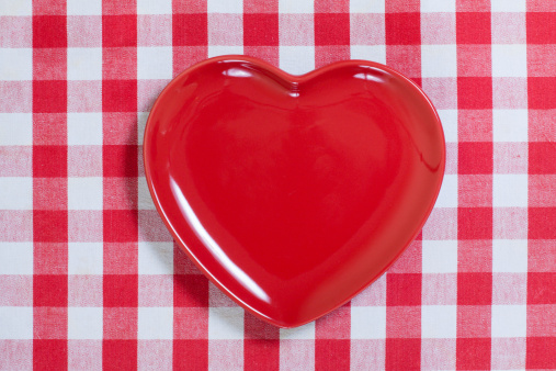 Heart shape plate on red and white kitchen textile texture background