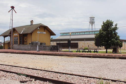 Bertram, TX - June 8, 2023: Historic Train Depot with Library in Background on Cloudy Day in Bertram TX