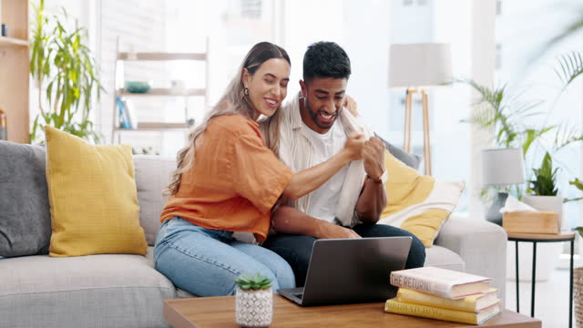 Good news, video call and happy couple with laptop celebrating on sofa, hug and excited in living room. Online, winner and man embrace woman in celebration of lottery, success or home loan approval