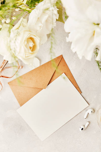 istock Beige crafting paper envelope mock up for greetings, invitation, postcard, text among white flowers and earphones. Biophilic interior, cozy home. Copy space. 1539573708