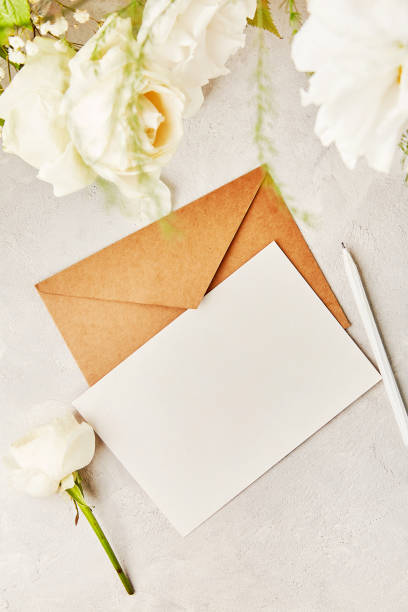 istock Beige crafting paper envelope for greetings, invitation, postcard, text among white flowers. Biophilic interior, cozy home. Copy space. 1539573731