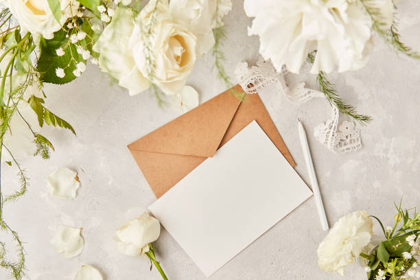 istock Aesthetic pastel paper background- mock up and envelope for invitation, wishing, postcard, text among white eustoma, roses and gypsophila top view. Biophilic interior, cozy home. Copy space 1539573744
