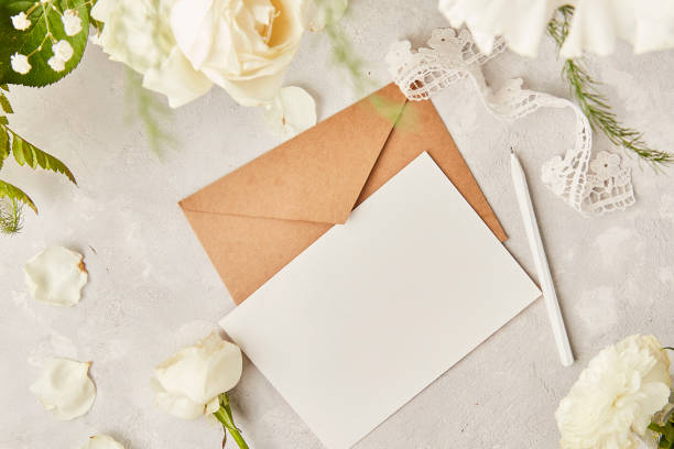 istock Aesthetic pastel paper background- mock up and envelope for invitation, wishing, postcard, text among white eustoma, roses and gypsophila top view. Biophilic interior, cozy home. Copy space 1539573746