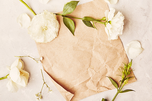 Aesthetic crafting vintage paper for mock up, invitation, wishing, postcard among white flowers.