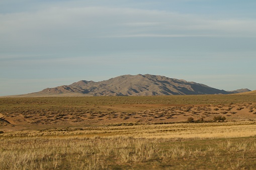 A barren landscape in the desert featuring sand dunes and patches of grass