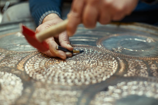 istock Craftsman doing engravings on a copper metal plate 1539576854