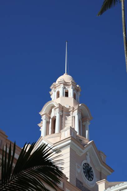istock Historic courthouse clock situated atop a tall building, with a palm tree in the foreground 1539599560