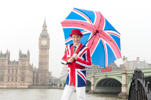 British man with Union Jack jacket, tie and umbrella, by the Thames, Westminster Bridge and the Houses of Parliament