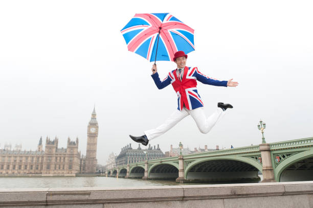 British man in Union Jack attire jumping along the embankment by the Thames.